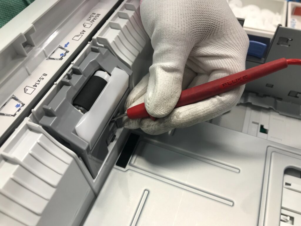 Dłoń w rękawiczce w czasie naprawy drukarki